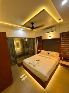 a bedroom with a large bed with white sheets at BBC Luxury Apartments in Perintalmanna