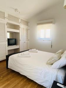 um quarto com uma cama branca e uma televisão em Duplex Marina de Vilamoura em Vilamoura