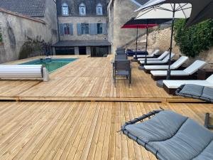 una terraza con tumbonas y una piscina con sombrilla en LE CHARME DE ST PIERRE en Saint-Pierre-le-Moûtier