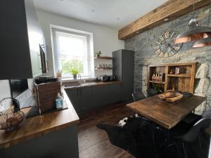 a kitchen with a table and a stone wall at The Lowry .. Where elegance meets Luxury! in Oban