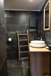 a bathroom with a sink and a tv on the wall at Maison de village - Les Voûtes Blanches - Serre Chevalier 1350 in Saint-Chaffrey +16 photos