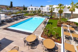 uma imagem de uma piscina num resort com mesas e cadeiras em Van der Valk Hotel Bloom em Saint-Aygulf