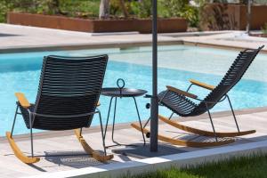 two chairs and a table next to a pool at Van der Valk Hotel Bloom in Saint-Aygulf