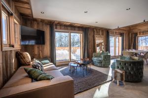 a living room with a couch and chairs and a tv at Chalets Choseaux Lézami in Saint-Sorlin-dʼArves