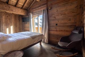 a bedroom with a bed and a chair and a window at Chalets Choseaux Lézami in Saint-Sorlin-dʼArves