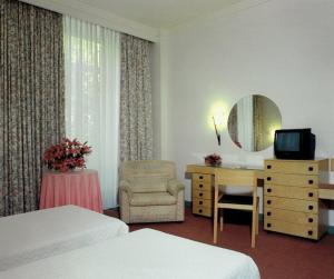 a hotel room with two beds and a desk and a mirror at Hotel Das Termas in Geres