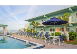 a pool with chairs and a table with an umbrella at Via Roma Beach Resort in Bradenton Beach