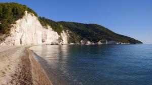 a sandy beach next to the water with a mountain at HMO Glamping & Suites in Vignanotica in Mattinata