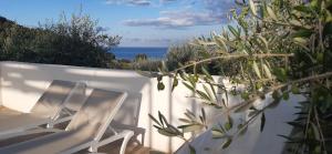 two white chairs on a white fence with the ocean at HMO Glamping & Suites in Vignanotica in Mattinata