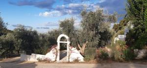a white arch in a garden with trees and flowers at HMO Glamping & Suites in Vignanotica in Mattinata