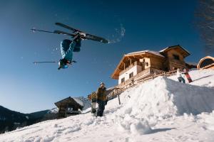 a skier doing a trick in the air over a pile of snow at Gut Stein Panoramalodge in Mühlbach am Hochkönig