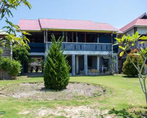 um pinheiro em frente a uma casa em Yuni Surf House em Lagudri
