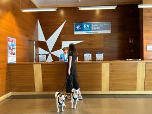 RVHotels Nautic Park في بلاتخا دي آرو: a woman walking two dogs in front of a counter