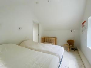 ein weißes Zimmer mit 2 Betten und einem Stuhl in der Unterkunft L'atelier de Durbuy in Durbuy