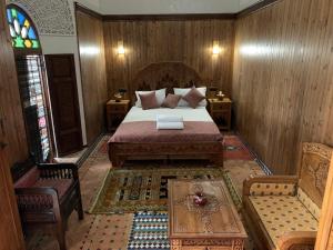 a bedroom with a bed and a table and a chair at Riad Palais Marouane in Meknès