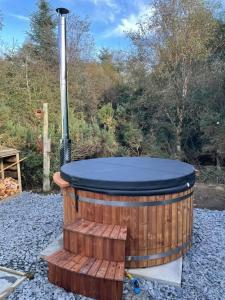 a wooden hot tub with a black top sitting on gravel at Slaley Retreat in Slaley