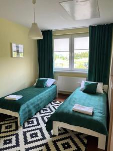 Apartament Hemingwaya في يلينيا غورا: غرفة نوم بسريرين ونافذة ذات ستائر خضراء