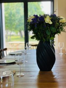 um vaso preto com flores sobre uma mesa de madeira em La grange du Pigeonnier authenticity and gentleness 10 minutes from Tours em La Riche