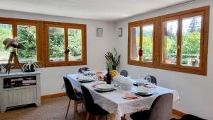 a dining room with a table with chairs and windows at Chalet Falcon With Hot Tub in Chamonix-Mont-Blanc