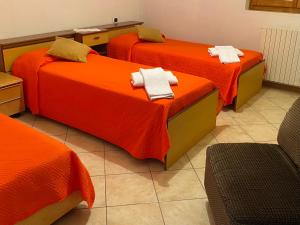 three beds in a room with orange sheets at Villa Gianna in Limone sul Garda