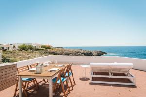 patio ze stołem i krzesłami oraz oceanem w obiekcie Binibeca Sunset w mieście Sant Lluis