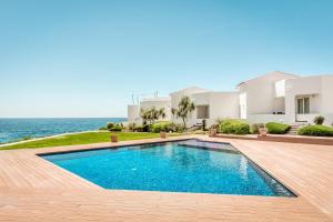 a swimming pool in front of a house with the ocean at Binibeca Sunset in Sant Lluis
