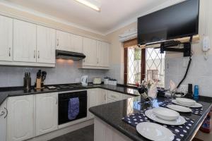 una cucina con armadi bianchi e piano di lavoro nero di Dunwerkin Bachelor Flat a Kenton-on-Sea