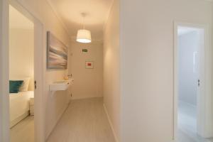 einen Flur, der zu einem Zimmer mit einem Bett und einem Fenster führt in der Unterkunft Apartamento Jardins da Falésia in Albufeira + 16 Fotos
