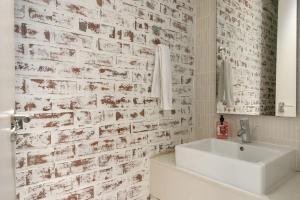 a bathroom with a white sink and a brick wall at Melrose Arch Luxury Apartment - WITH GENERATOR in Johannesburg +9 photos