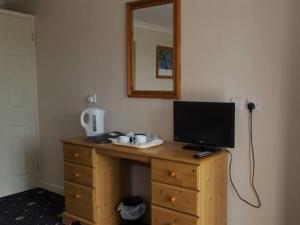 uma secretária com uma televisão em cima de uma cómoda de madeira em A35 Pit Stop Rooms em Axminster