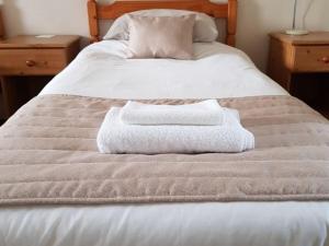 uma cama com duas toalhas em cima em A35 Pit Stop Rooms em Axminster