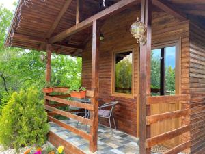 Cette cabane en bois dispose d'une terrasse avec une table et une chaise. dans l'établissement Grădina de Vară “La Cristian”, à Filipeştii de Tîrg