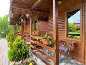 une terrasse couverte d'une maison en bois avec une chaise et des fleurs dans l'établissement Grădina de Vară “La Cristian”, à Filipeştii de Tîrg