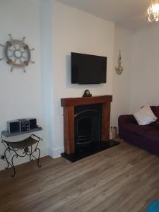 a living room with a fireplace with a flat screen tv at Anchor cottage in Flamborough