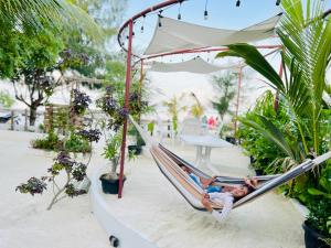 Ein Mann, der in einer Hängematte im Garten liegt. in der Unterkunft Pelican Beach Maafushi in Maafushi