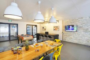 a dining room with a table and a tv on a brick wall at Résidence Nemea Aix Campus 2 in Aix-en-Provence