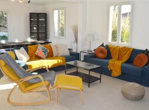 una sala de estar con sofás azules y sillas amarillas. en Villa Marie-Josée, en Le Muy