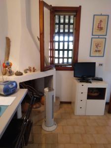 a living room with a television and a desk with a computer at Villetta Kala E Moru Sa oghe e su mare in Geremèas