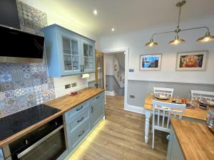 a kitchen with blue cabinets and a table in it at Pass the Keys Beautifully Presented 3BR Luxury Apartment in Kirkcudbright