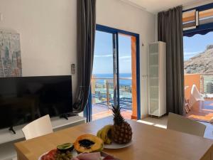 a dining room with a table with a plate of fruit on it at Apartment with views of sea and mountains in Taurito