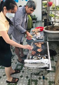 um homem e uma mulher a cozinhar comida num grelhador em Shiny Homestay Da Nang em Da Nang