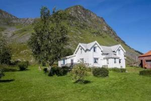 uma casa branca num campo com uma montanha em Mor's hus em Valle