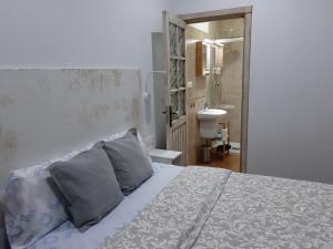 ein Schlafzimmer mit einem Bett mit zwei Kissen und einem Badezimmer in der Unterkunft Dormir en Cádiz in Cádiz