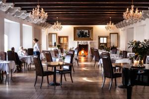 een eetkamer met tafels en stoelen en een open haard bij Skrøbelev Gods Manor House in Rudkøbing