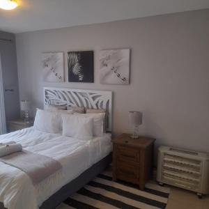 a bedroom with a white bed and two pictures on the wall at Home relaxation in the city in Cape Town