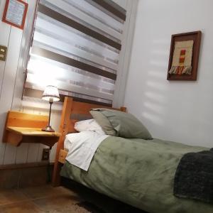a bedroom with a bed and a table and a window at B&B HMüller in Pucón