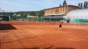 two people playing tennis on a tennis court at Esmarin wellness hotel in Mníšek pod Brdy