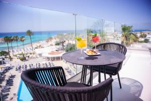 a table with a plate of food and a drink on a balcony at Pavlo Napa Beach Hotel in Ayia Napa