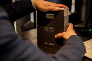 a man in a suit is holding a book at Hotel Restaurant de Echoput in Apeldoorn