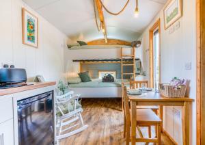 um pequeno quarto com uma cama, uma mesa e uma cozinha em Elephant View Shepherds Hut em Caernarfon